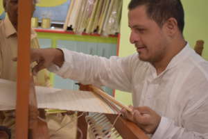 Adult weaving a rug on the loom (skill building)