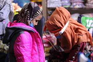 volunteer helping in wear jacket to girl
