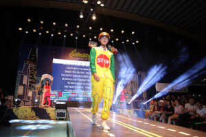 Students in road safety outfits walk the runway.