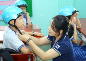 A volunteer helps adjust a student's helmet.