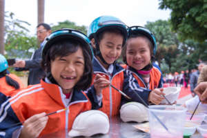 Students enjoy painting helmet sculptures.