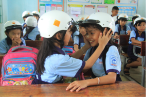 Students help each other put on their new helmets.