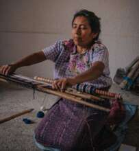 Dolores weaving a brocade design from home