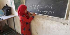 Gul Naz writes on the chalkboard