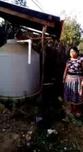 Beneficiary with her rainwater harvesting system