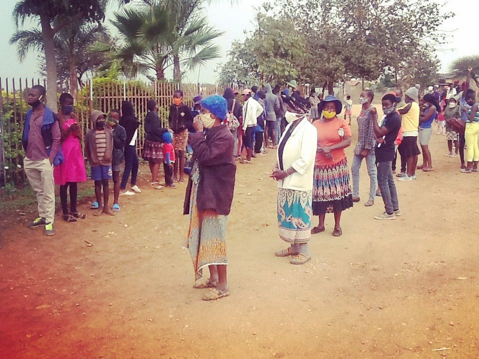 Caregivers and children wait for monthly groceries