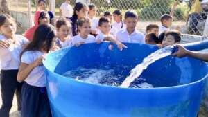 Children at school watch water delivering.