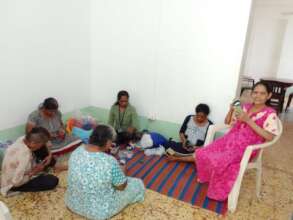 Instructor training the women in making handicraft