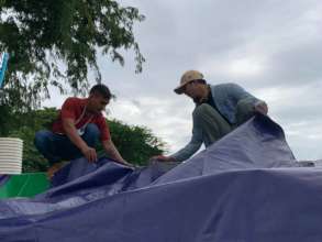 Mr. Sun (left) helps put tarps on homes