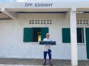 Head teacher in front of the new school building