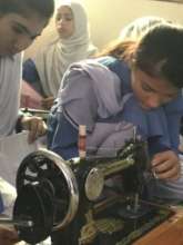 Two young girls who are learning to sew