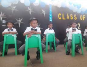 Learners perform a hat dance for their parents