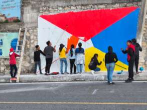 Middle school students paint background of mural