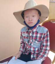 A young boy receives a new wide-brimmed hat.