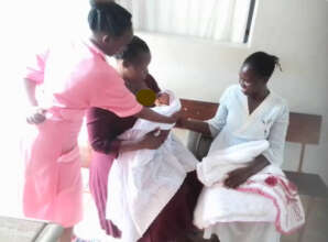A nurse teaching a mother on how to nurse her baby