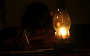 Girl studying in the street with oil lamp