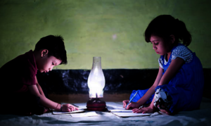 Children studying in the street with oil lamp