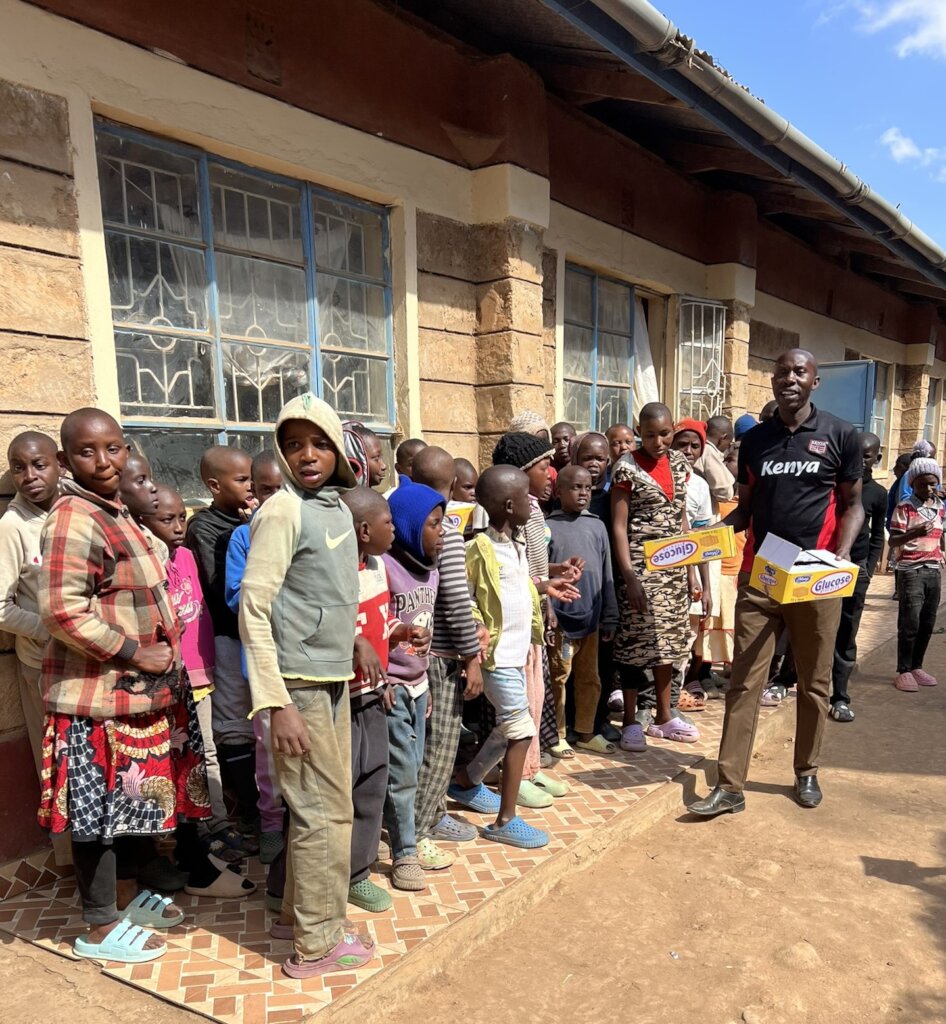 Teacher Francis with biscuits for pupils at Thinu