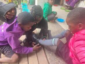 Everyone helps Geoffrey put on his shoes