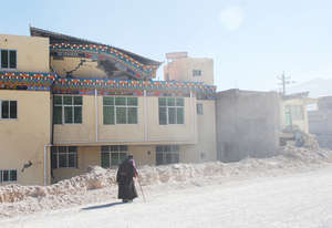 old woman walking down ruined street