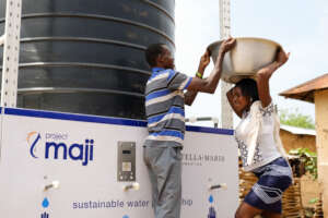 Woman collecting water from Project Maji kiosk