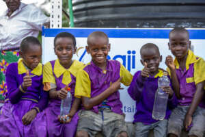 Community children sit by the Project Maji Kiosk