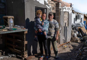 Mother holds her son & stands with her husband.