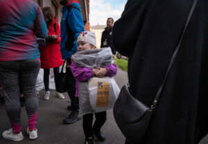 Young girl holds blankets, received by the IRC