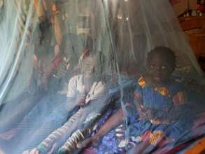 Agness and her kids under their mosquito net