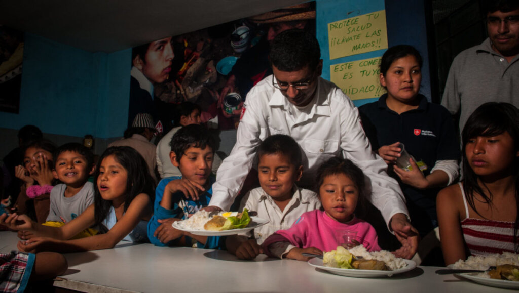 Feeding children in San Juan Bautista, Peru