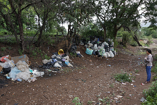 Denis in front of piles of garbage