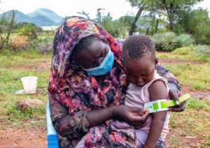 A mother measures her child for malnutrition.