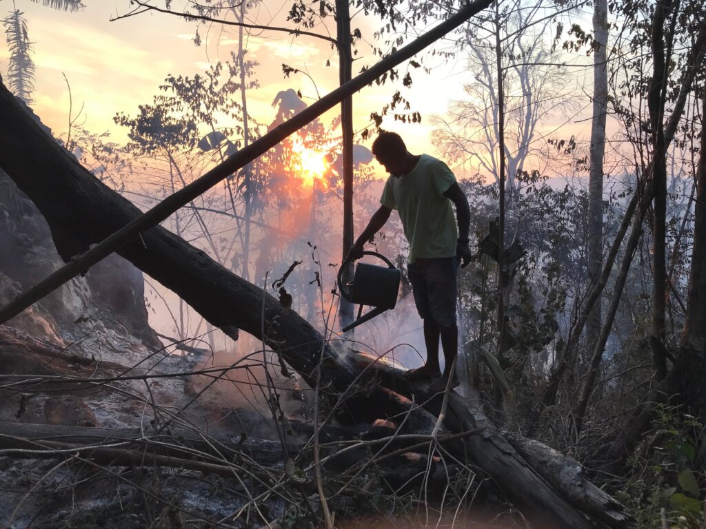 Village member putting out fire with watering can