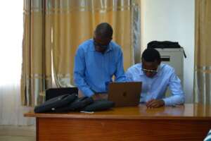 A picture of two men using a Macbook on a table.