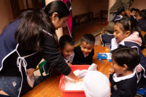 Teacher and students making pan de muerto