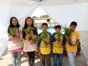 Students showing their carrot and cucumber harvest