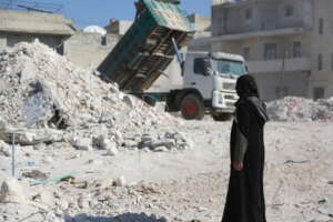woman standing in front of collapsed building