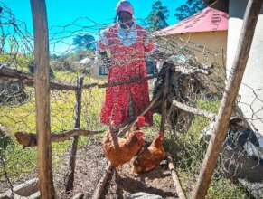 Nomusa stands behind her chicken coop