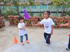 Two students using sticks to hold up plastic cone