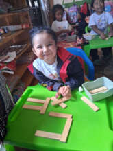 Student smiling behind table of wood block letters