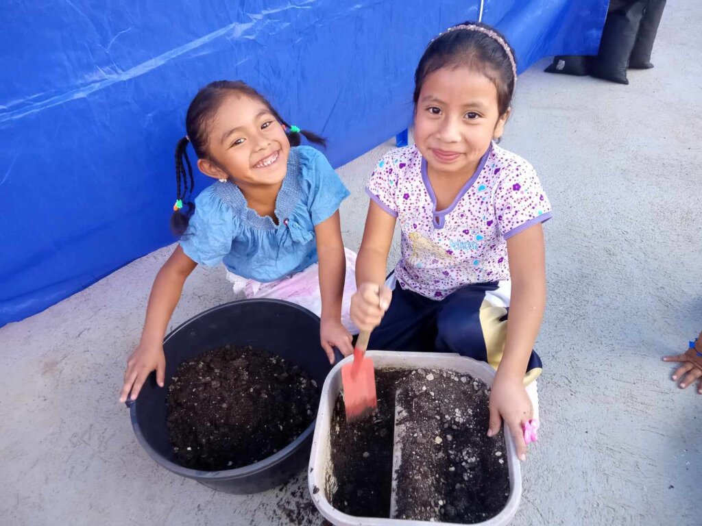 2 students preparing soil for planting seeds