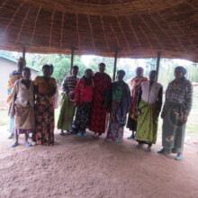 women learning from an old thatched bungalow