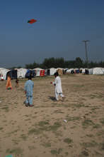 Children flying their kite near makeshift homes...