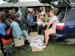 Volunteer providing shoes for children of Gioto