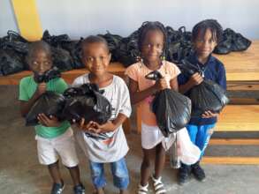 Children hold bags full of rice and beans