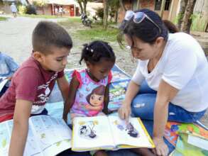 W4C leader Ciria Tores helps a girl learn to read