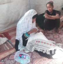 Embroiderer in her displacement shelter, Gaza