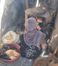 Woman baking bread at a displacement shelter, Gaza
