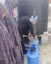 Queueing for water at a displacement shelter, Gaza