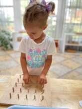 Young girl putting bands around pegs